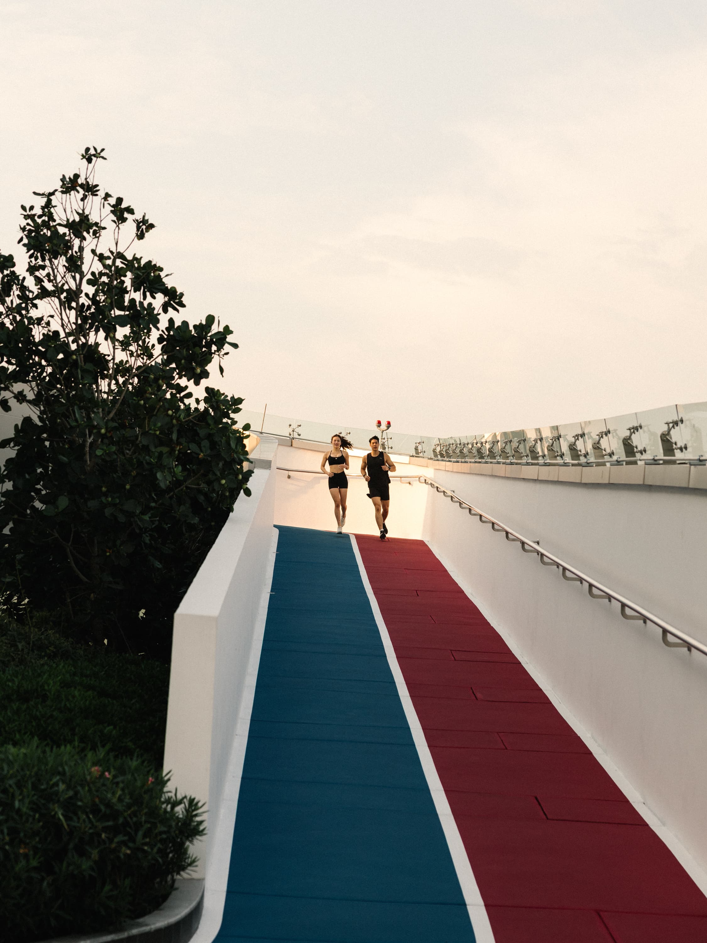 Two runners on a rooftop track at golden hour