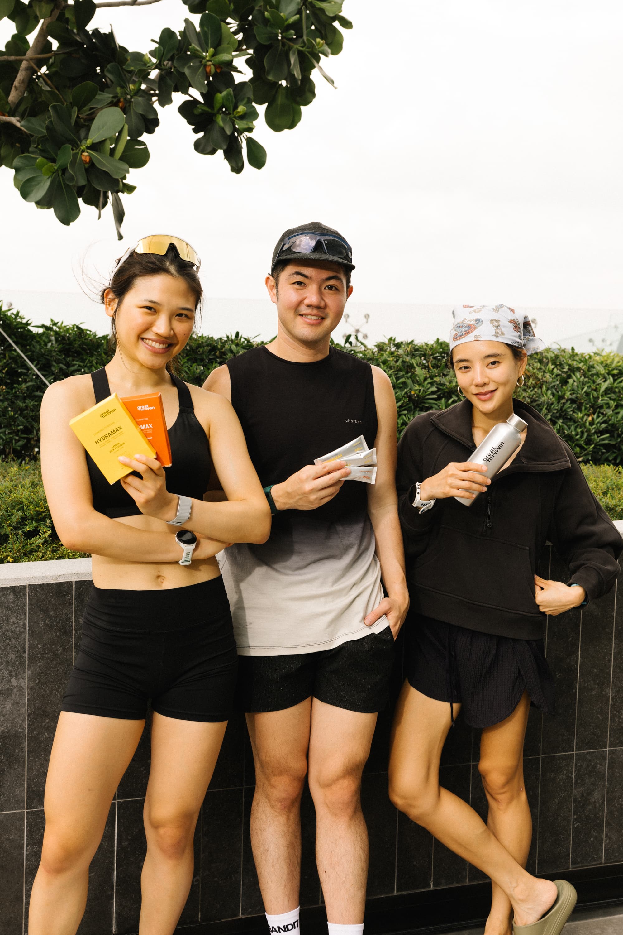 Three athletes holding HYDRAMAX boxes, sachets, and a bottle