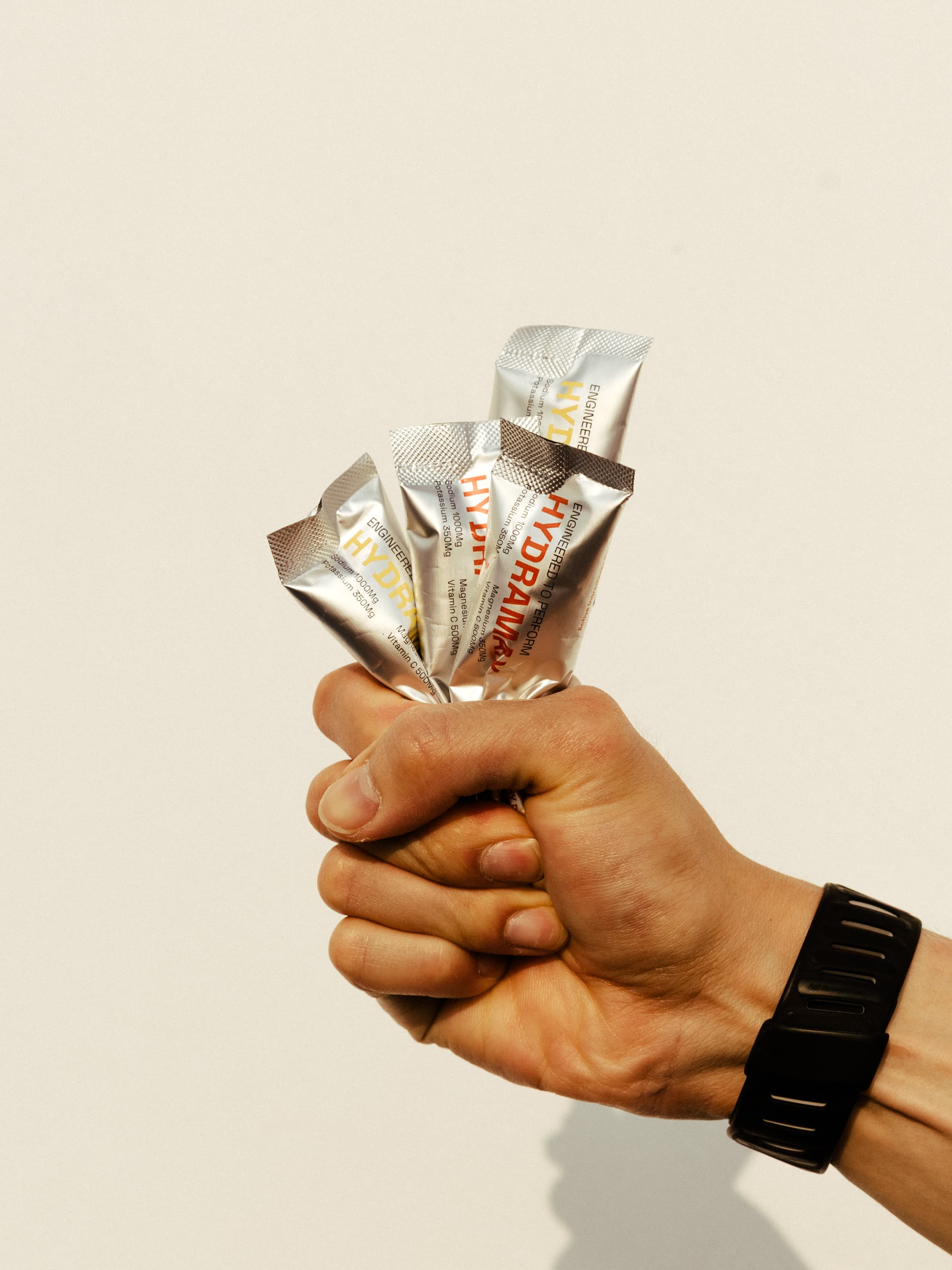 A fist holding several individual HYDRAMAX sachets